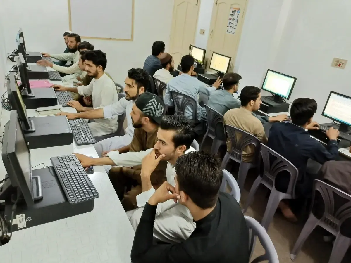 Side view of students working at computer workstations in the academy lab